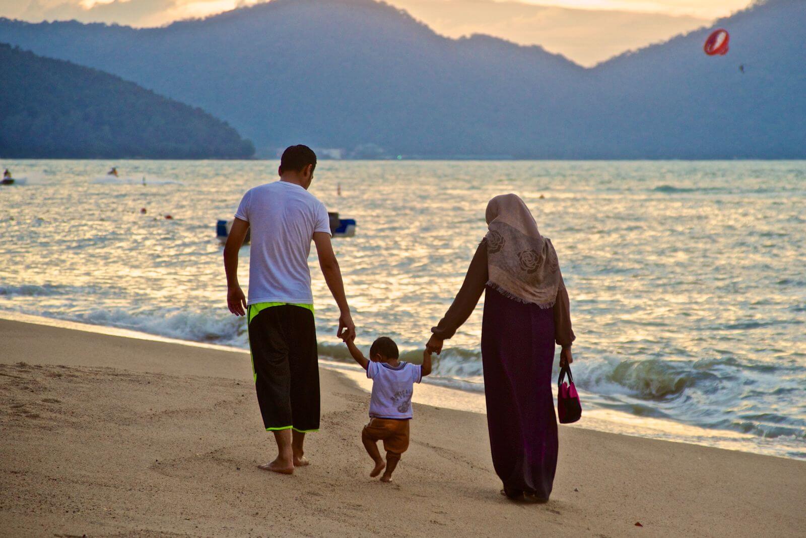 muslim family walking on the beach